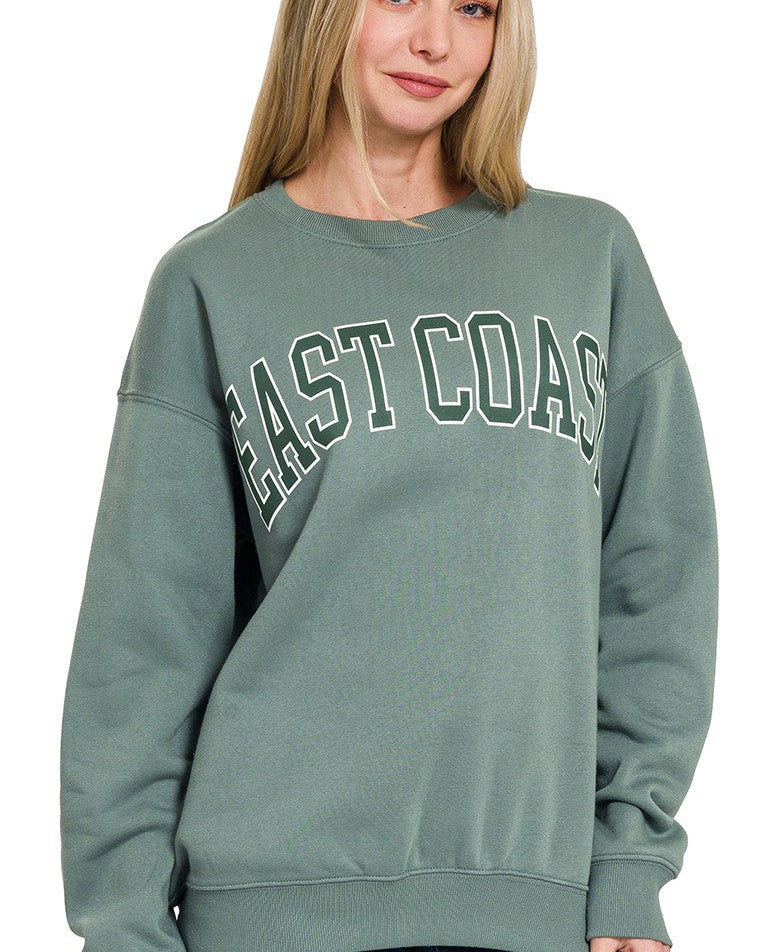 Woman wearing a green sweatshirt with 'East Coast' text on a white background
