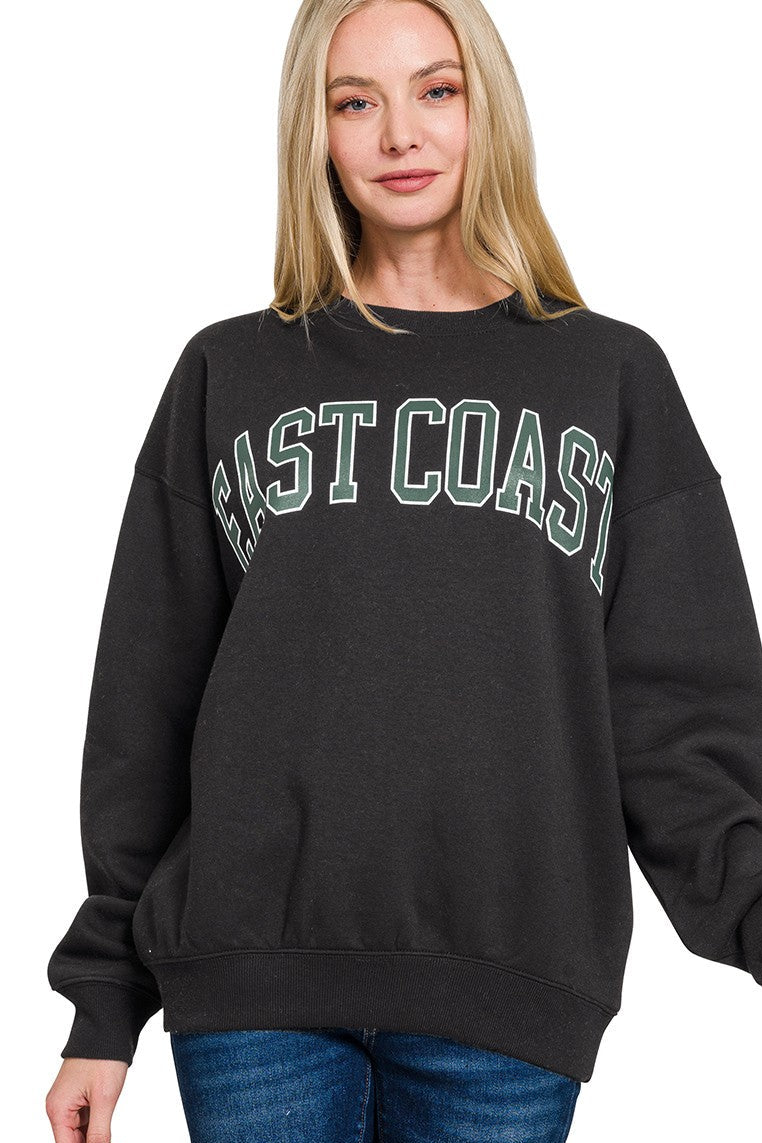 Woman wearing a black sweatshirt with 'East Coast' text on a white background